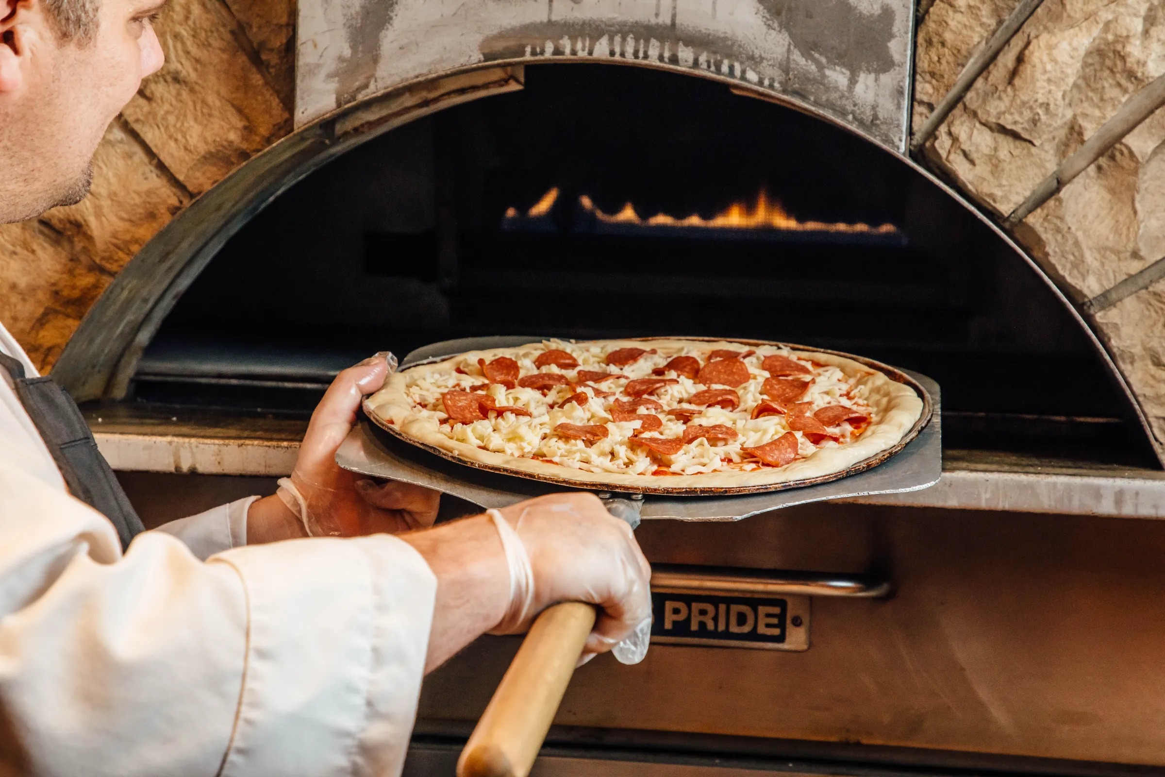 Chef placing pizza in brick oven
