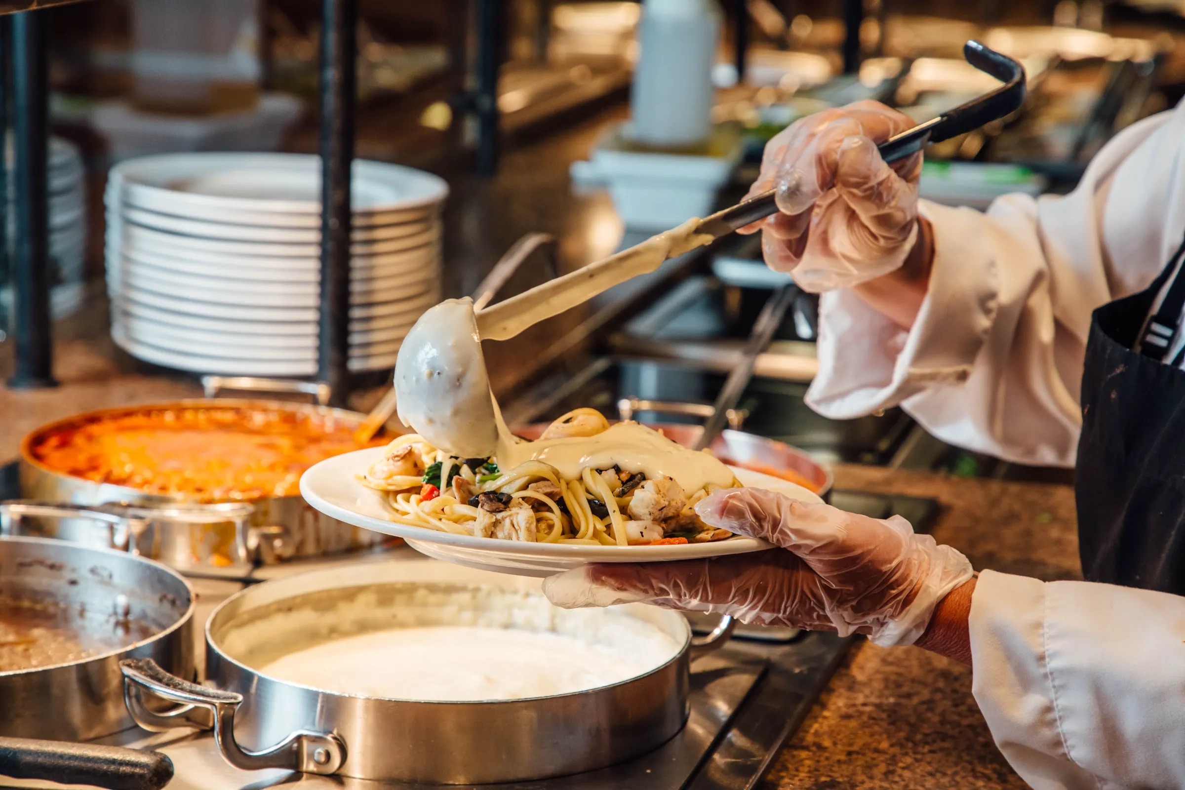 Chef pouring sauce over pasta