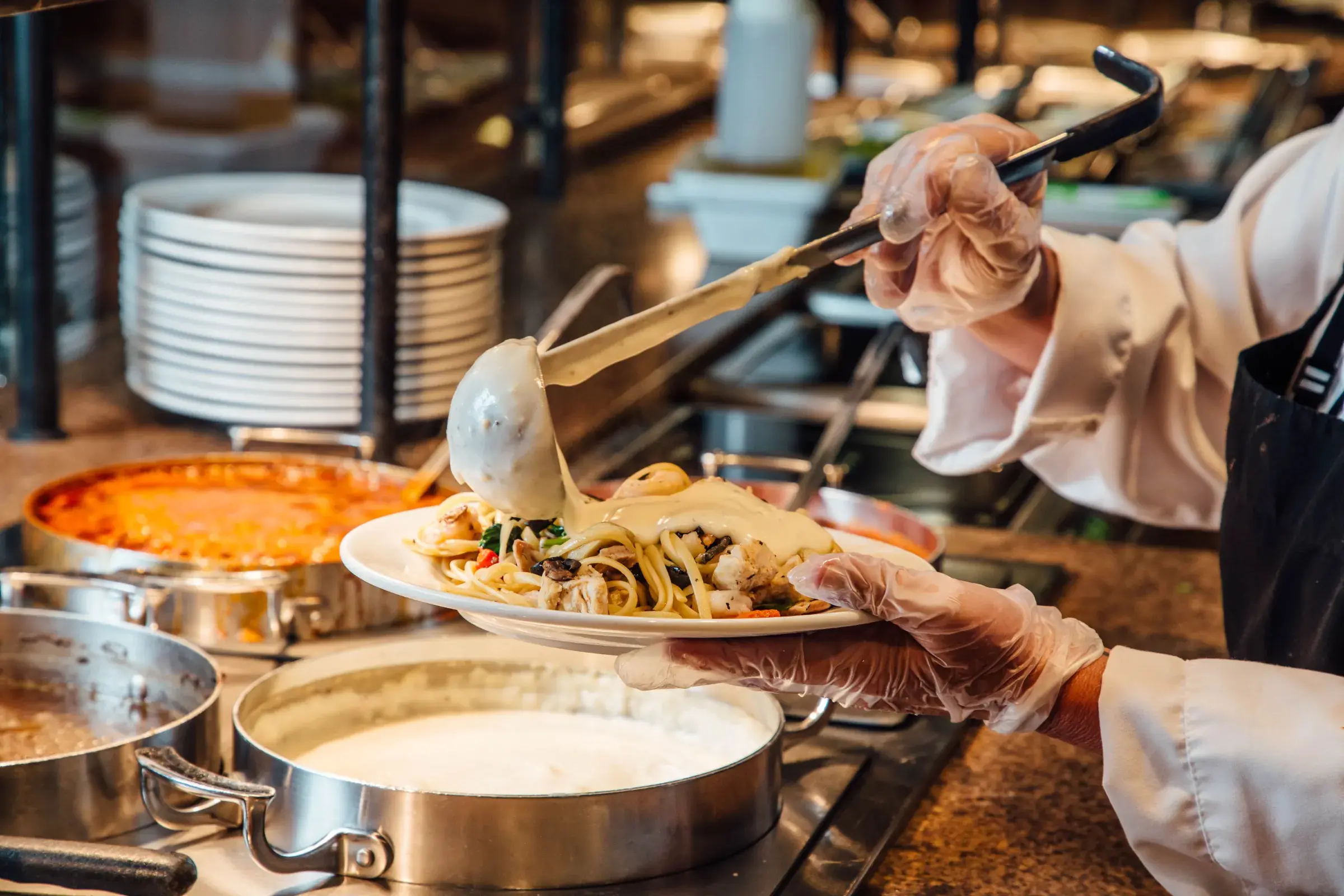 Chef pouring sauce over pasta