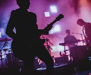 Band playing on stage with pink and purple stage lights.